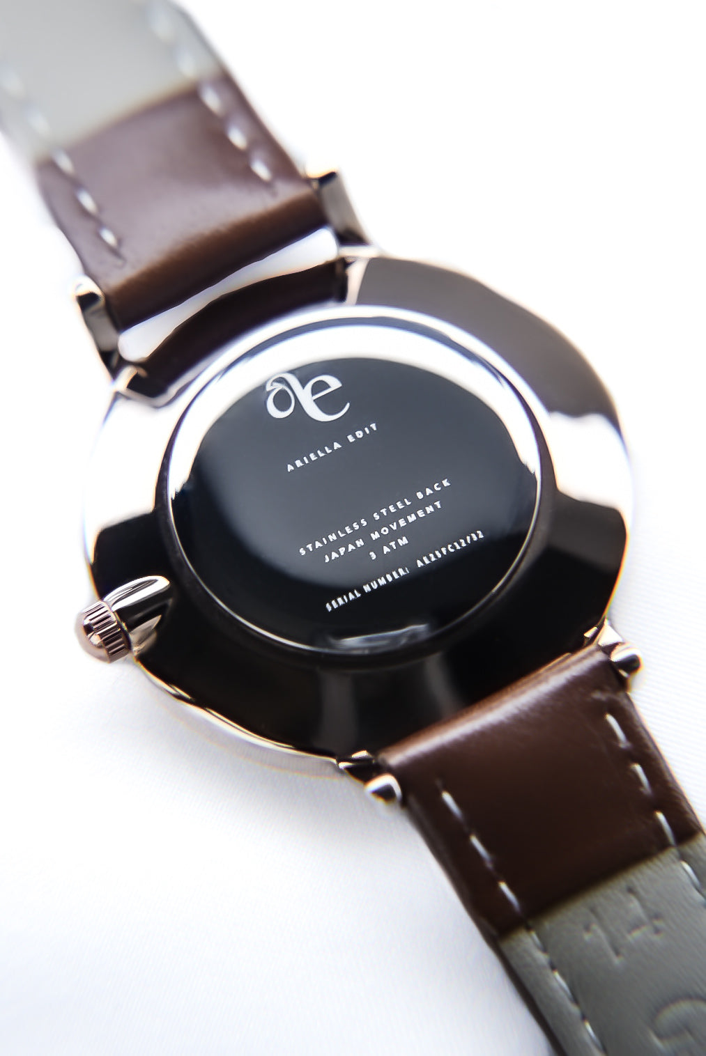Close-up of a watch with a brown leather strap on a white background