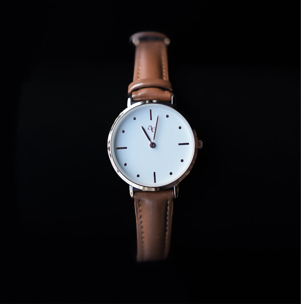 Wristwatch with brown leather strap and white dial on a black background