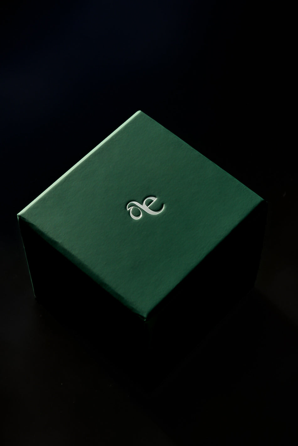 Green gift watch box with a logo on a black background