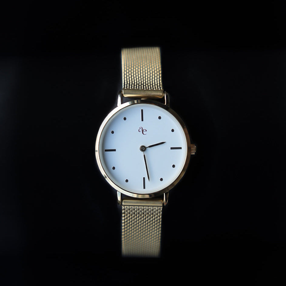 Wristwatch with a gold mesh strap on a black background